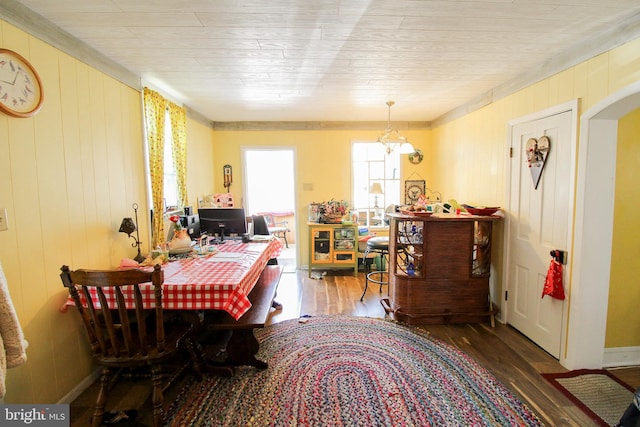 dining room featuring a notable chandelier, wooden walls, and hardwood / wood-style floors