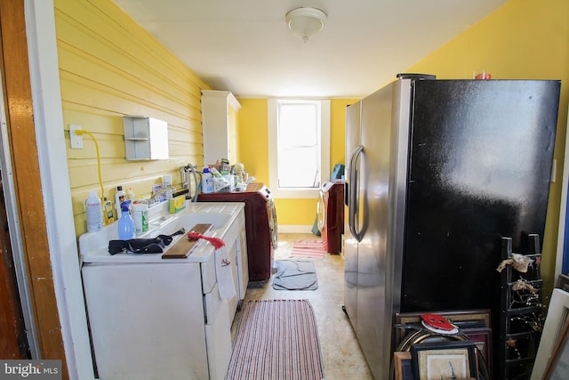 kitchen featuring refrigerator with ice dispenser and wooden walls