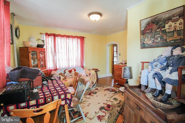 bedroom featuring ornamental molding, arched walkways, baseboards, and wood finished floors