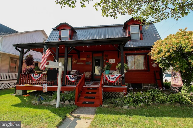 view of front of home with metal roof, a porch, and a front yard