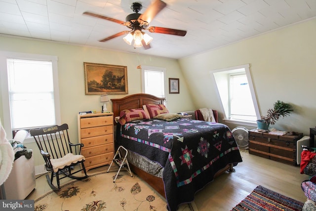 bedroom with light wood-style floors, ornamental molding, and ceiling fan