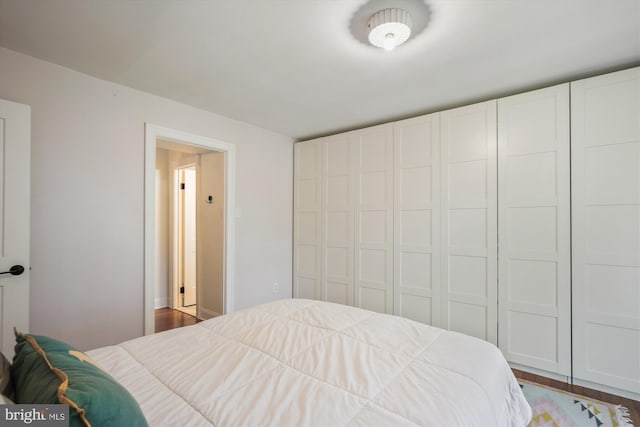 bedroom with dark hardwood / wood-style flooring and a closet