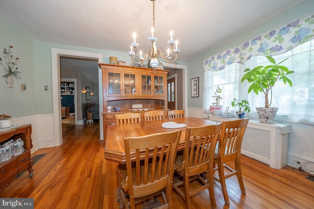 dining area featuring an inviting chandelier, hardwood / wood-style floors, and radiator heating unit