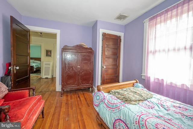 bedroom with multiple windows and hardwood / wood-style flooring