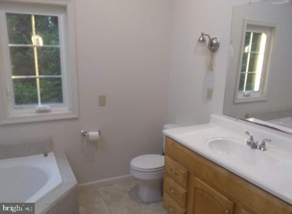 bathroom with a wealth of natural light, tile patterned floors, vanity, and toilet