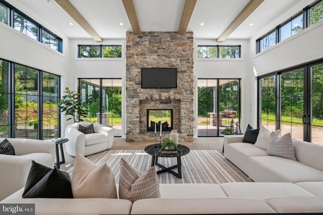 living room featuring beamed ceiling, light hardwood / wood-style floors, and a wealth of natural light