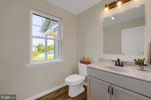 bathroom with vanity, wood finished floors, visible vents, baseboards, and toilet