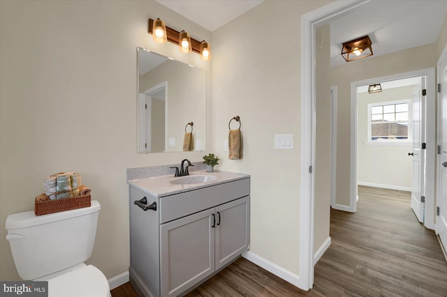 bathroom featuring toilet, vanity, baseboards, and wood finished floors