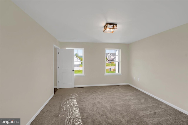 spare room featuring carpet flooring, visible vents, and baseboards