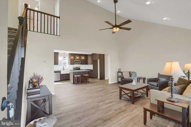 living room featuring light wood finished floors, ceiling fan, stairs, recessed lighting, and high vaulted ceiling