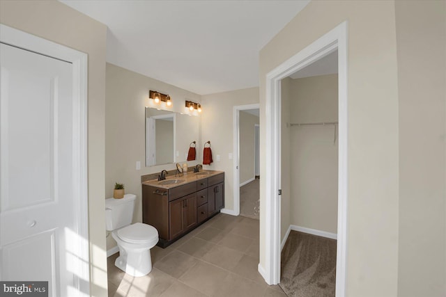 bathroom featuring double vanity, a spacious closet, toilet, and a sink