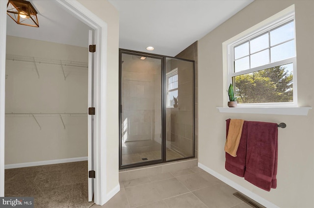 full bathroom with a walk in closet, visible vents, baseboards, and a stall shower