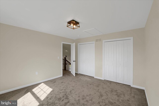 unfurnished bedroom with multiple closets and carpet flooring