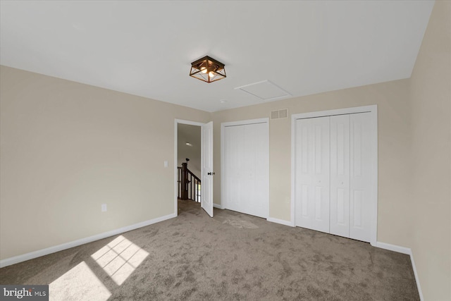 unfurnished bedroom with visible vents, carpet floors, two closets, and baseboards