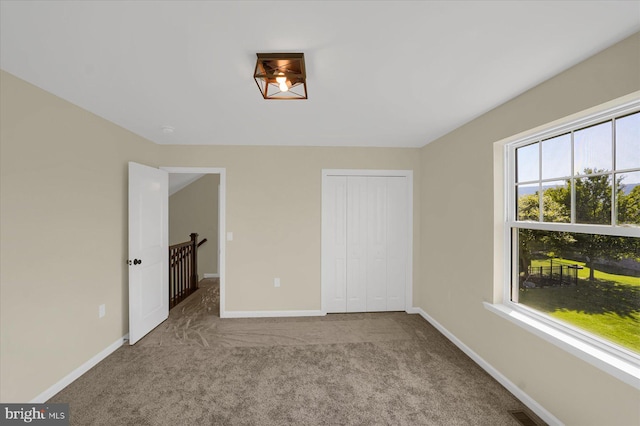 unfurnished bedroom with a closet and light colored carpet