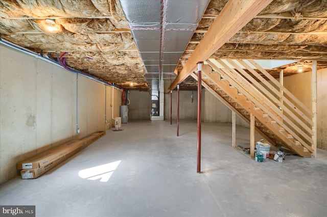 unfinished below grade area featuring stairs and water heater