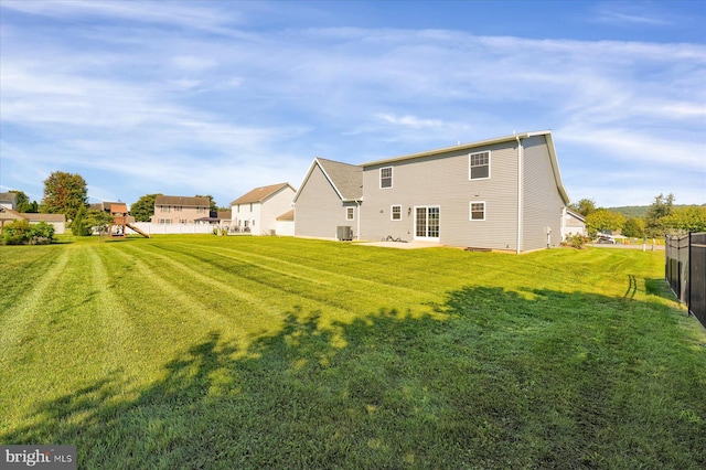 rear view of property with central AC, a playground, and a yard