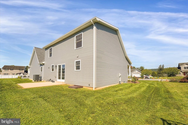 rear view of property with a lawn, a patio, and central AC