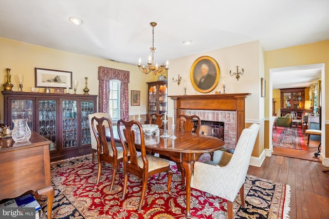 dining area featuring a fireplace, dark hardwood / wood-style flooring, and a notable chandelier