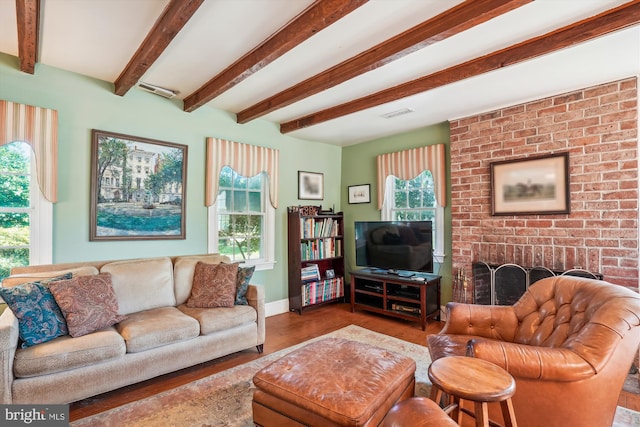 living room with wood-type flooring, beamed ceiling, a fireplace, and a healthy amount of sunlight