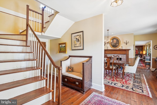 stairway featuring wood-type flooring, vaulted ceiling, and a chandelier