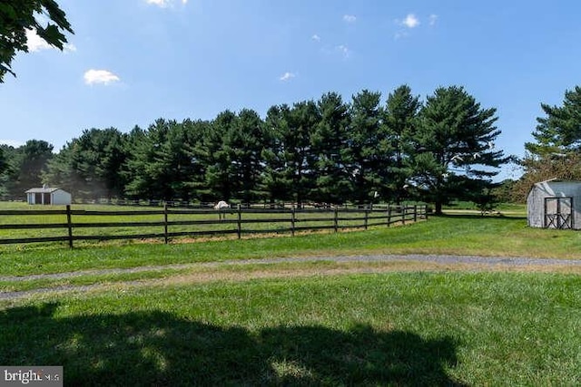 view of yard with a storage shed and a rural view