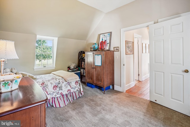 bedroom featuring light wood-type flooring and vaulted ceiling