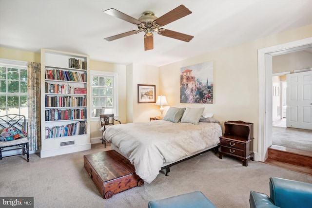 bedroom featuring multiple windows, ceiling fan, and light colored carpet