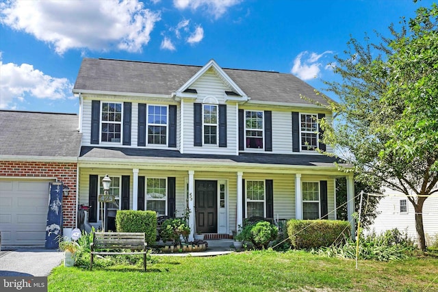 colonial inspired home with a garage, covered porch, and a front yard