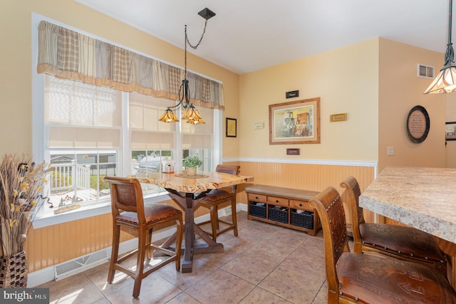 dining space featuring a wainscoted wall, wood walls, visible vents, and tile patterned floors