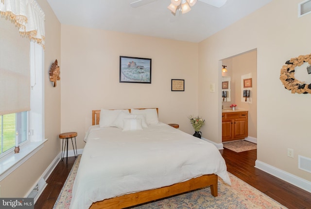 bedroom with dark wood-style floors, visible vents, ensuite bathroom, a ceiling fan, and baseboards