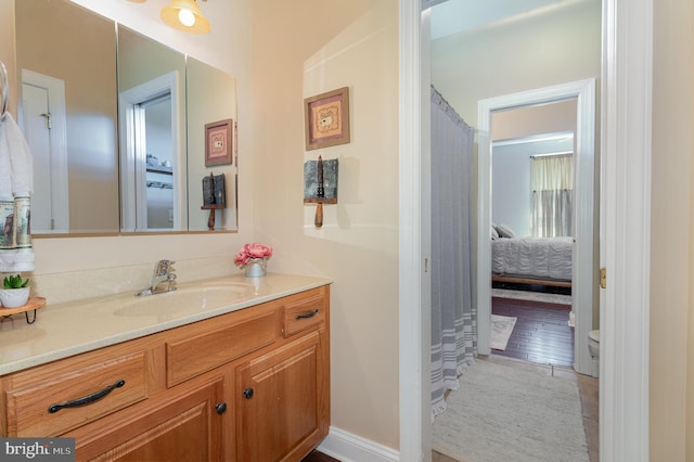 ensuite bathroom with baseboards, ensuite bath, vanity, and toilet