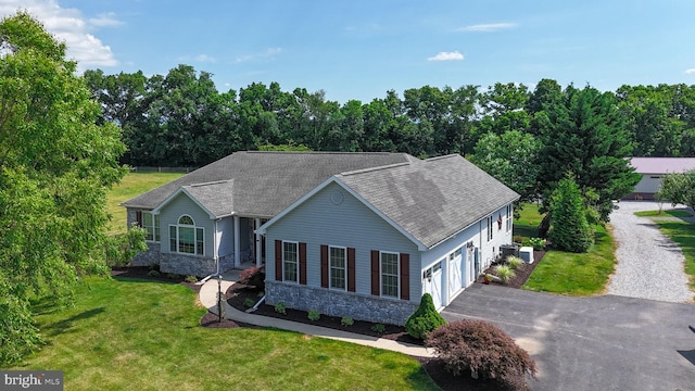 ranch-style home featuring a garage, a shingled roof, stone siding, aphalt driveway, and a front lawn