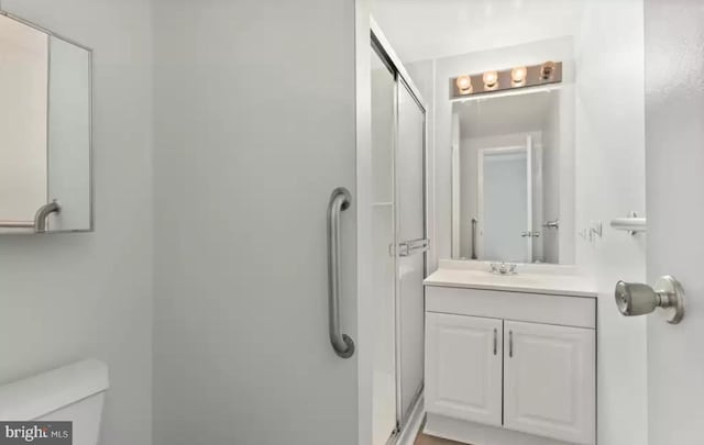 bathroom with an enclosed shower, vanity, and toilet