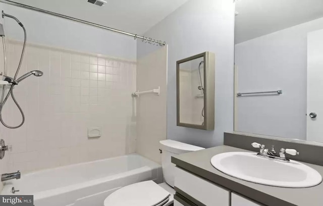 full bathroom featuring vanity, tiled shower / bath combo, and toilet