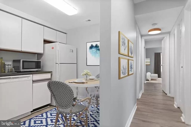 kitchen with white appliances, light hardwood / wood-style floors, and white cabinetry