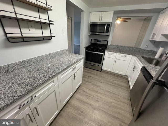 kitchen featuring stainless steel appliances, white cabinetry, ceiling fan, and light hardwood / wood-style floors