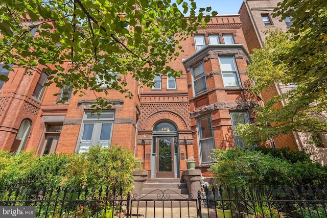 view of front facade featuring a fenced front yard, a gate, and brick siding