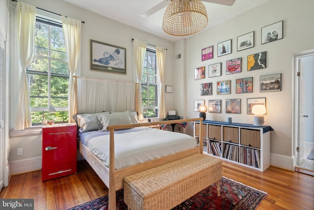 bedroom featuring ceiling fan, hardwood / wood-style floors, and multiple windows