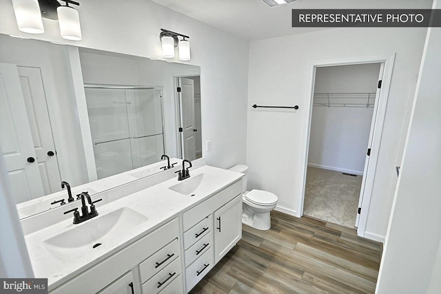 bathroom with vanity, toilet, wood-type flooring, and a shower with shower door