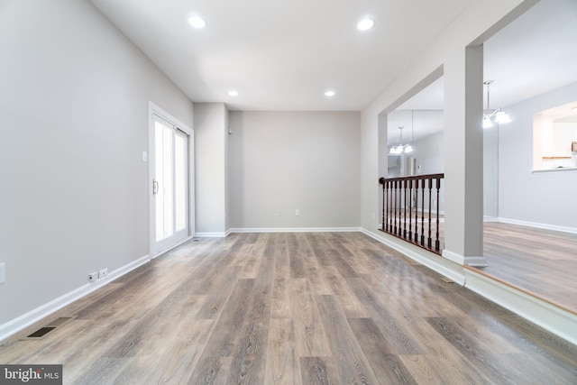 unfurnished room featuring wood-type flooring and a notable chandelier