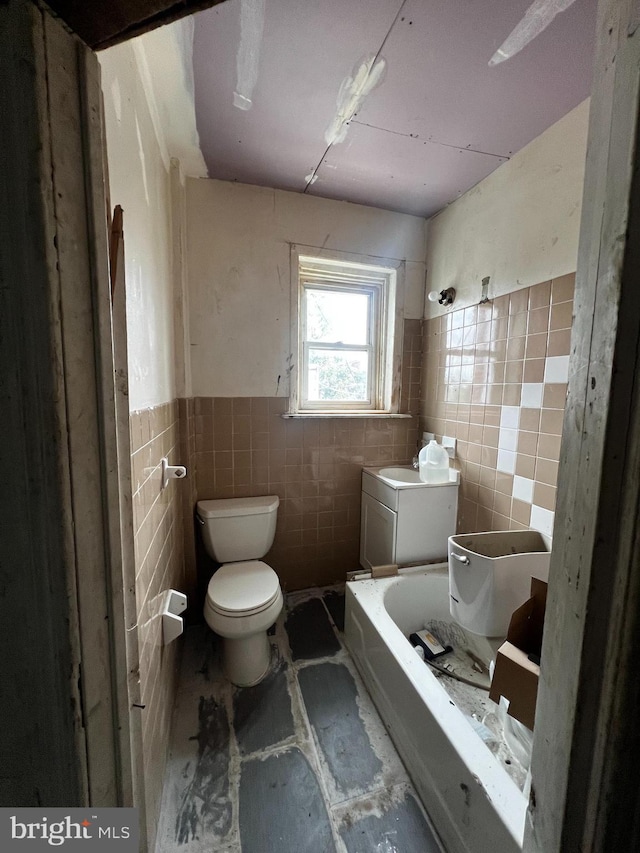 bathroom featuring a tub, tile walls, and toilet