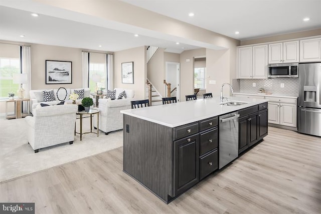 kitchen featuring light hardwood / wood-style flooring, appliances with stainless steel finishes, white cabinetry, sink, and an island with sink