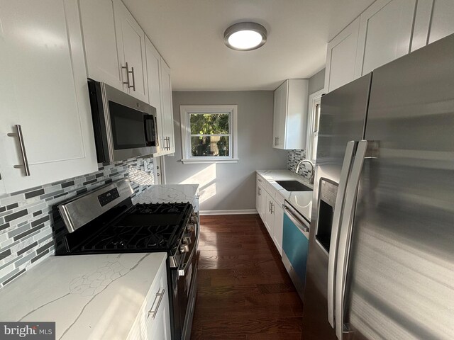 kitchen featuring appliances with stainless steel finishes, dark wood-type flooring, white cabinets, backsplash, and light stone countertops