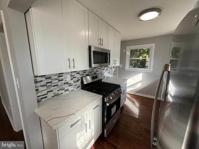 kitchen featuring white cabinets, dark wood-type flooring, stainless steel appliances, and light stone counters