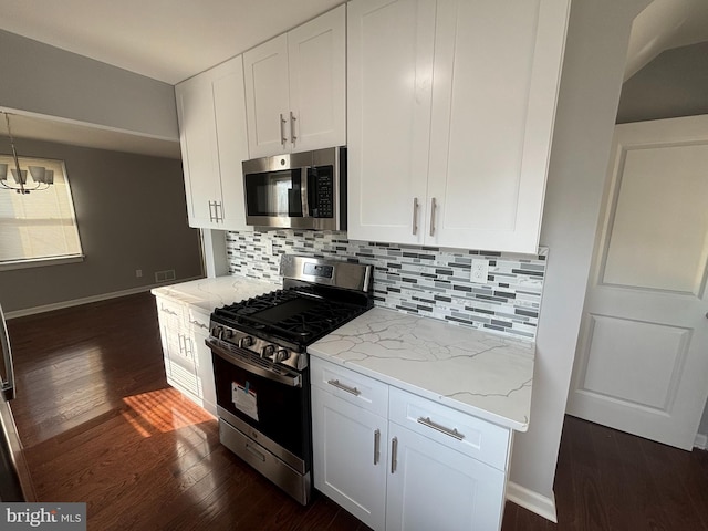 kitchen with dark wood-type flooring, light stone counters, decorative backsplash, appliances with stainless steel finishes, and white cabinetry