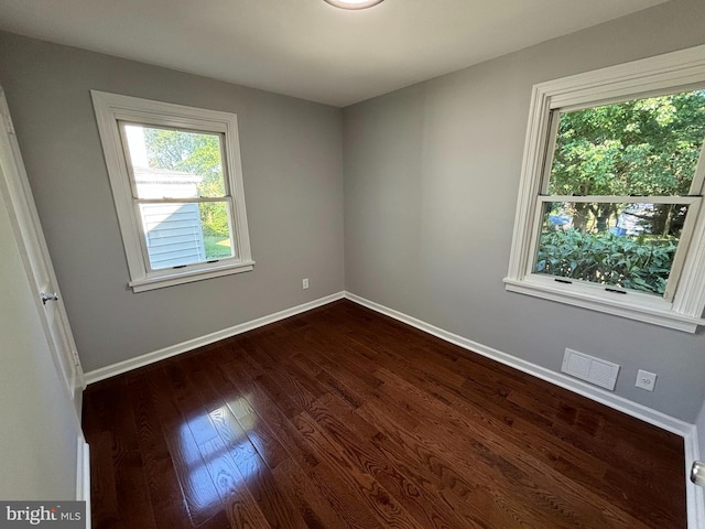 unfurnished room featuring visible vents, baseboards, and dark wood-type flooring