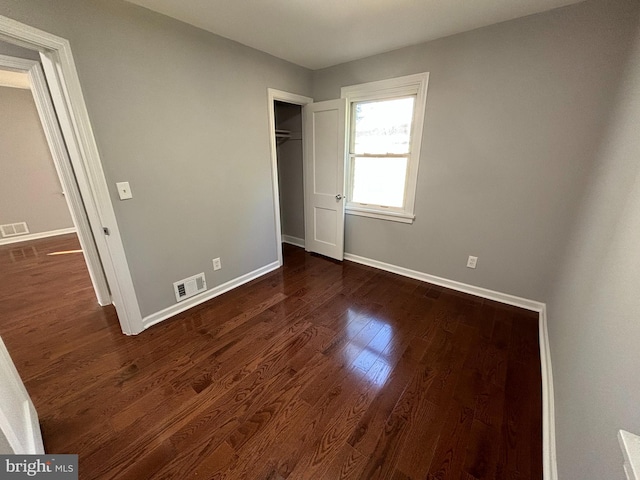 unfurnished bedroom featuring visible vents, baseboards, and dark wood-style flooring