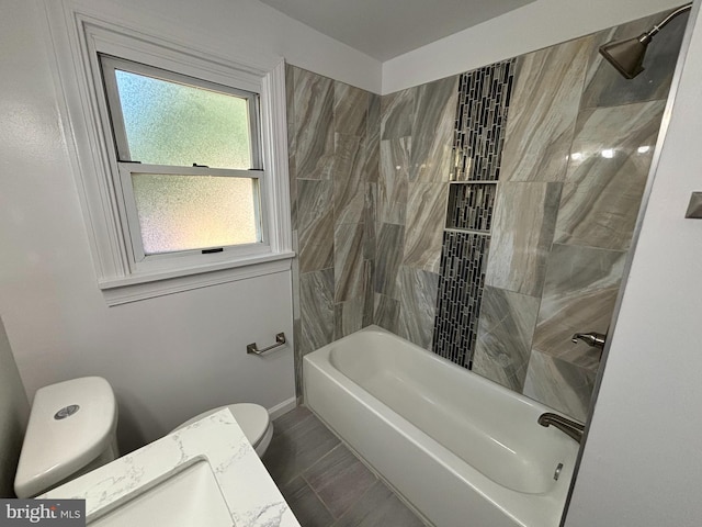 full bathroom featuring vanity, tiled shower / bath, and toilet