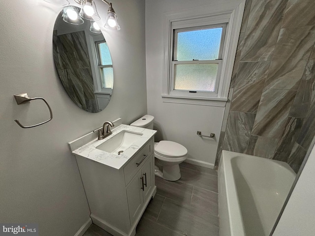 bathroom featuring vanity, toilet, baseboards, and a wealth of natural light